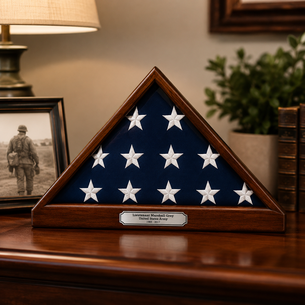A folded triangular military flag display case with a dark blue fabric interior, white stars, and a wooden frame sits on a polished wooden table. A small plaque at the base reads 'Lieutenant Marshall Grey Third Battalion 101st Airborne.