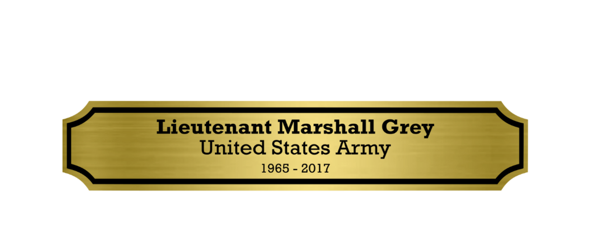 A rectangular gold memorial plaque for veteran flag shadow box with black border and black text reading 'Lieutenant Marshall Grey United States Army 1965 - 2017' on a plain white background.